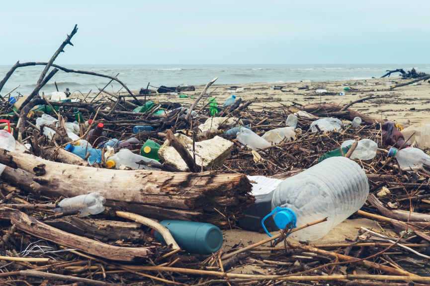 Spilled garbage on the beach of the big city. Empty used dirty plastic bottles. Dirty sea sandy shore the Black Sea. Environmental pollution. Ecological problem. Bokeh moving waves in the background